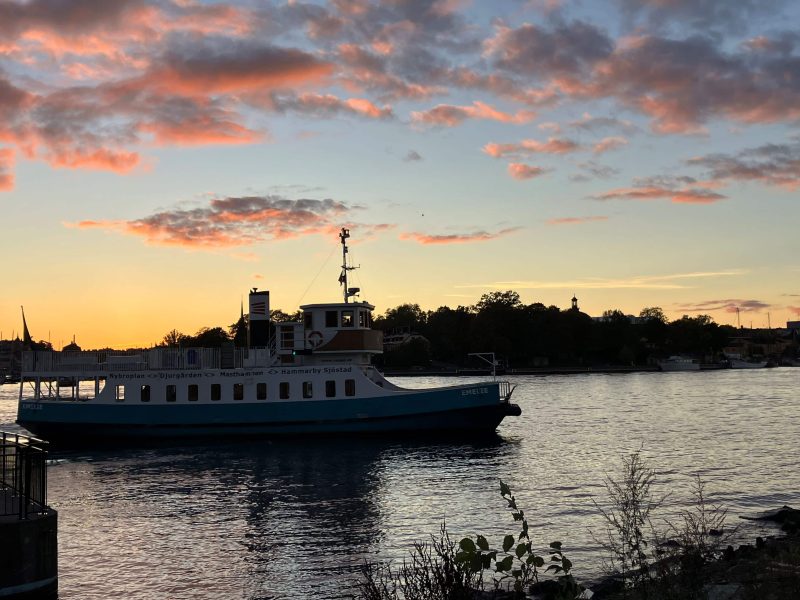 Ein kleines Schiff fährt während des Sonnenuntergangs durch Stockholm